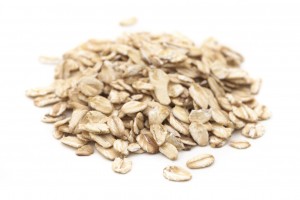 Oats heap on white background. Shallow depth of field, focus on the first oats.